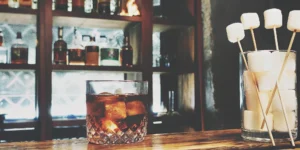 A glass of the best chocolate whiskey on ice, garnished with marshmallows.