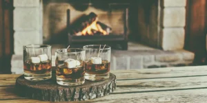 Glasses of smooth, sweet whiskey and marshmallows set by a cozy fireplace.