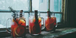 Cocktail jars with citrus, herb, and spice garnishes.