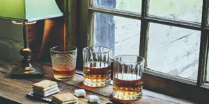 Three glasses of a good cheap whiskey for beginners served with s'mores on a table.