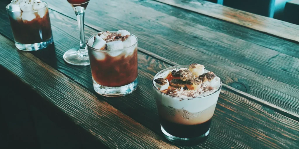Decadent dessert whiskey cocktails garnished with chocolate, cream, and marshmallows.