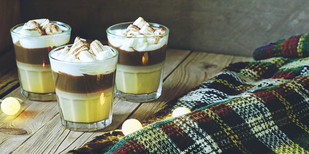 Creamy whiskey dessert drinks topped with whipped cream and toasted marshmallows.