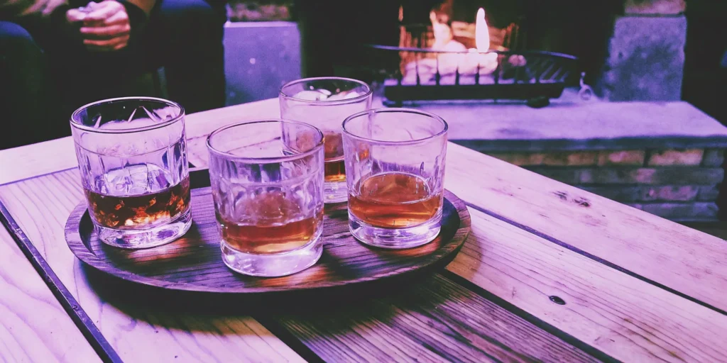 Four glasses of the most popular flavored whiskey on a tray by a cozy fireplace.