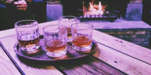 Four glasses of the most popular flavored whiskey on a tray by a cozy fireplace.