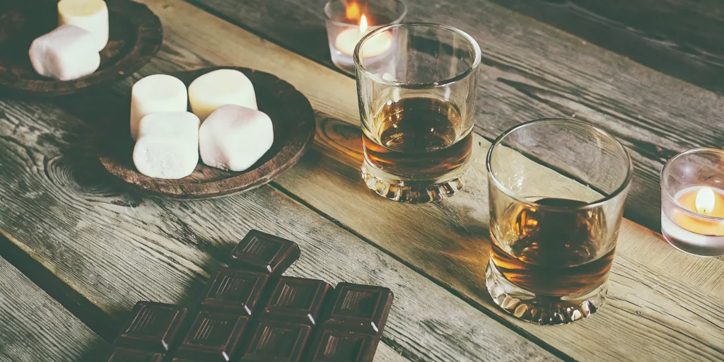 A row of the best tasting whiskey shots with chocolate and marshmallow garnishes.
