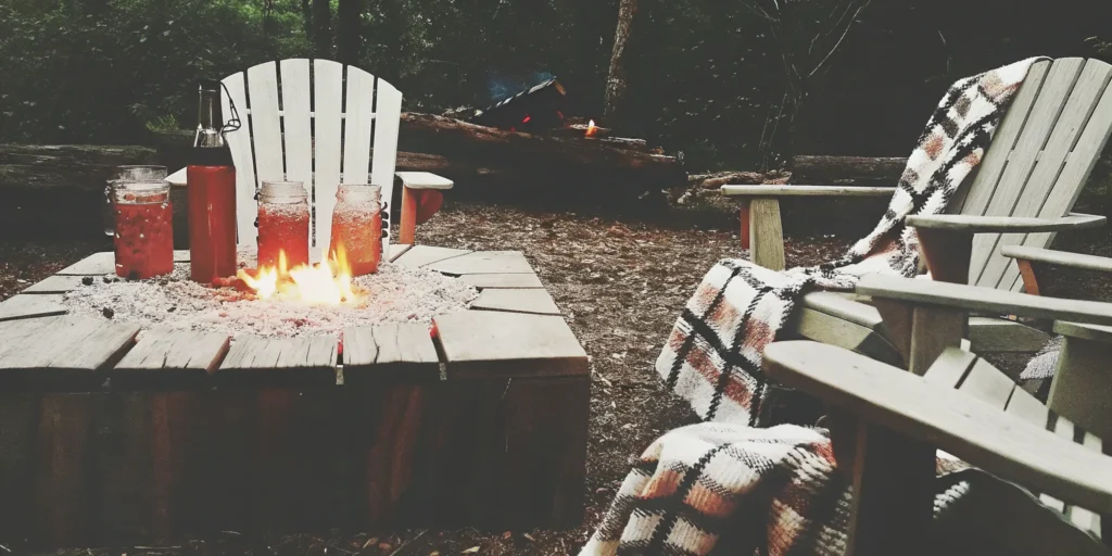 A batch of easy camping cocktails for a crowd served in mason jars by a campfire.