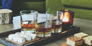 Sweet and smooth whiskey brands served with marshmallows and crackers on a wooden tray.