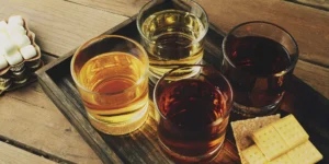A tasting of the best flavored whiskeys for beginners, served on a wooden tray.