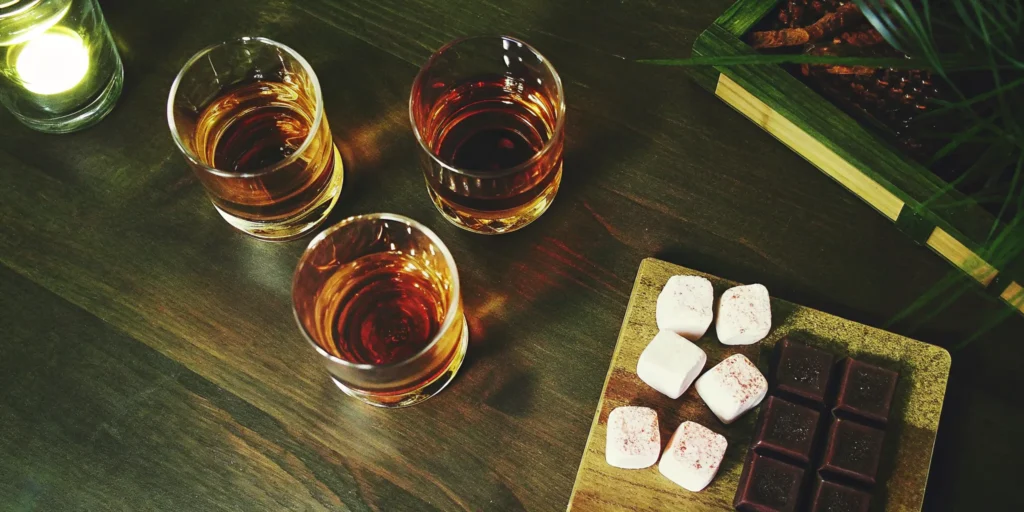 Three glasses of top sweet whiskey brands served with marshmallows and chocolate.