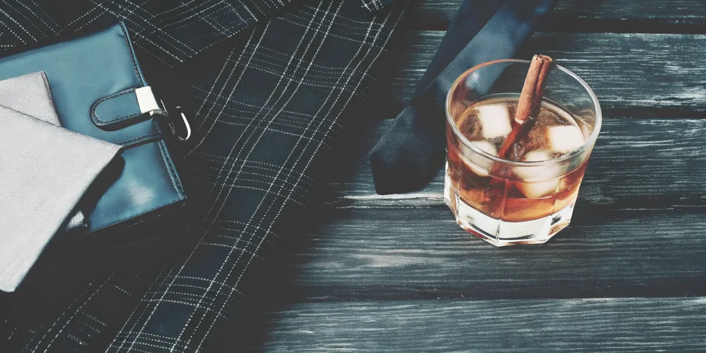 A glass of cinnamon graham cracker whiskey with ice and a cinnamon stick.