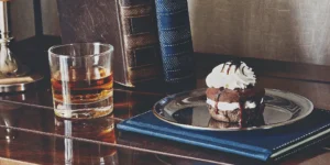 A glass of whiskey next to a chocolate dessert, an ideal whiskey for dessert pairing.