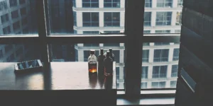 Ordering flavored whiskey for delivery on a smartphone with several bottles nearby.