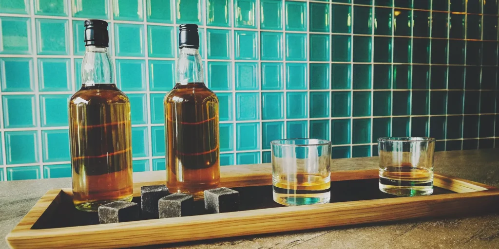 A review of two different s'mores flavored whiskey bottles with tasting glasses.