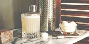 Marshmallow flavored liquor cocktail with ice, a bowl of marshmallows, and a cocktail shaker.