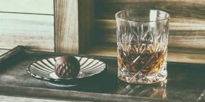 A smooth dessert sipper whiskey in a glass, paired with a chocolate truffle.