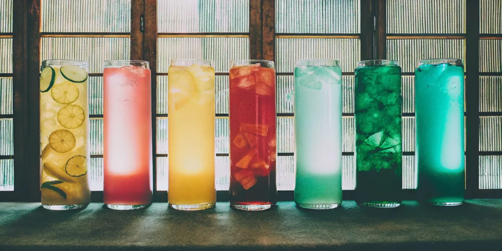 A variety of unique flavored spirits served in colorful cocktails on a bar.
