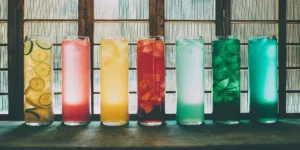 A variety of unique flavored spirits served in colorful cocktails on a bar.