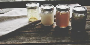 Camp cocktails in a jar on a rustic wood table, ready for an outdoor adventure.
