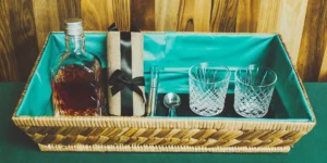 Creative bourbon gift basket idea with a bottle of whiskey, glasses, and bar tools.