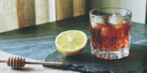 A honey bourbon drink from the recipe, served over ice with a lemon garnish.