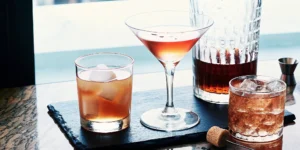 Brown sugar bourbon cocktails in various glasses, garnished with orange peel and ice.