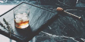 A honey bourbon cocktail recipe with a honey dipper and fresh garnish.