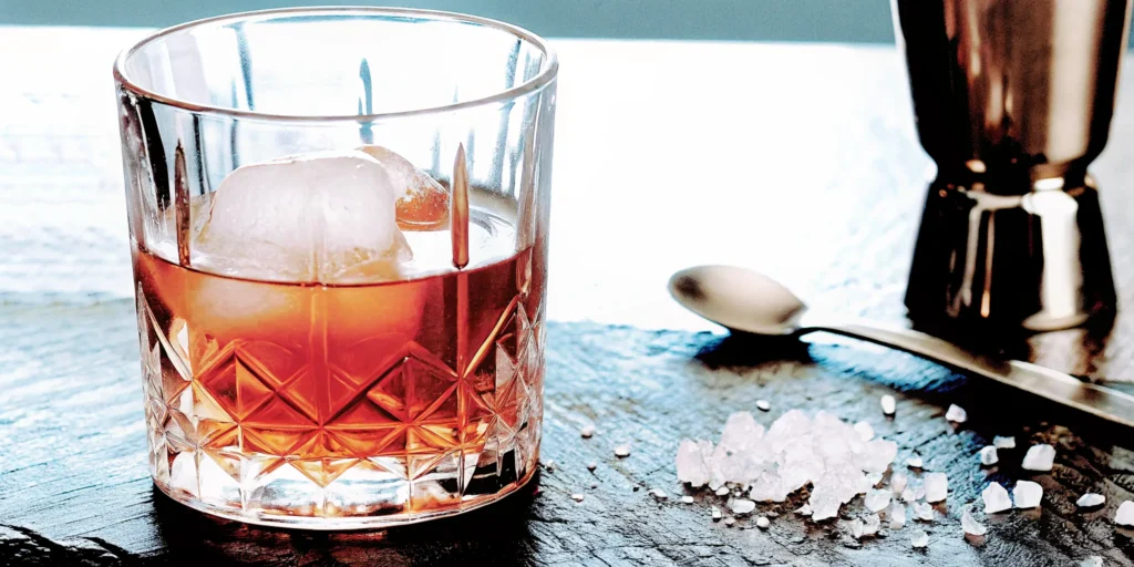 A glass of homemade salted caramel whiskey on the rocks with a salt garnish.