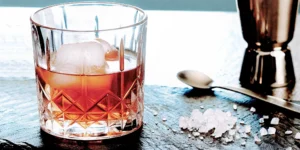 A glass of homemade salted caramel whiskey on the rocks with a salt garnish.