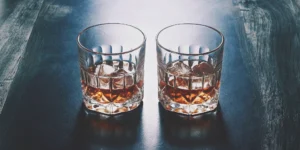 Whiskey chilled with ice cubes in one glass and with whiskey stones in another.