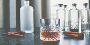 A glass of whiskey with cinnamon notes, garnished with cinnamon sticks.